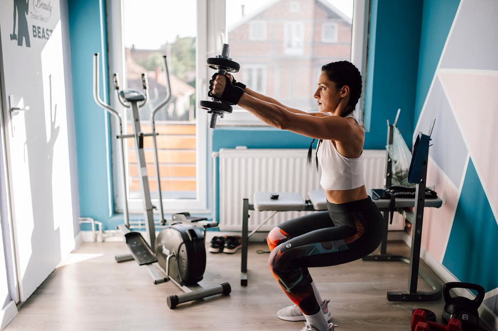 Person training with dumbbells in a bright home gym space